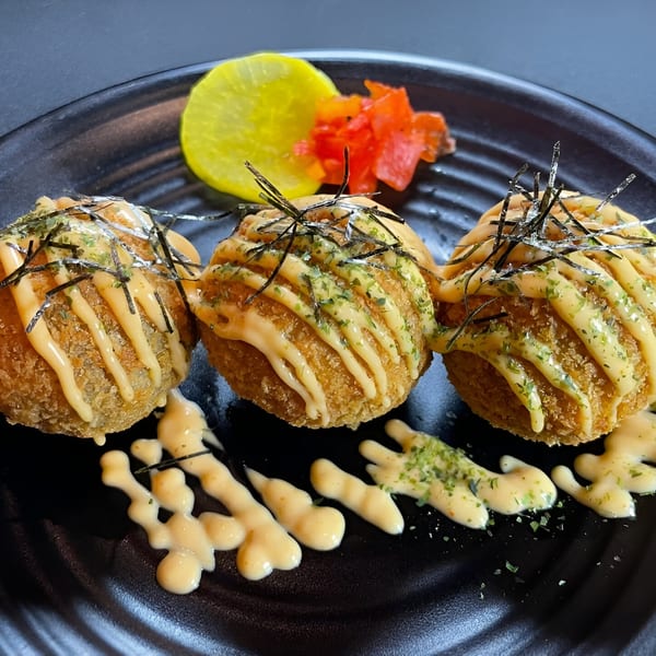 Three golden-fried Boru Ramen takoyaki balls drizzled with sauce, topped with seaweed, and served with pickled ginger.