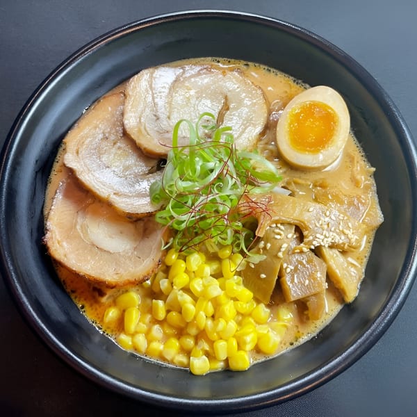 A bowl of Boru Ramen with pork, corn, bamboo shoots, a soft-boiled egg, and green onions.