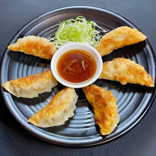 Six golden-brown Boru Ramen gyoza arranged around a small bowl of dipping sauce and shredded scallions.